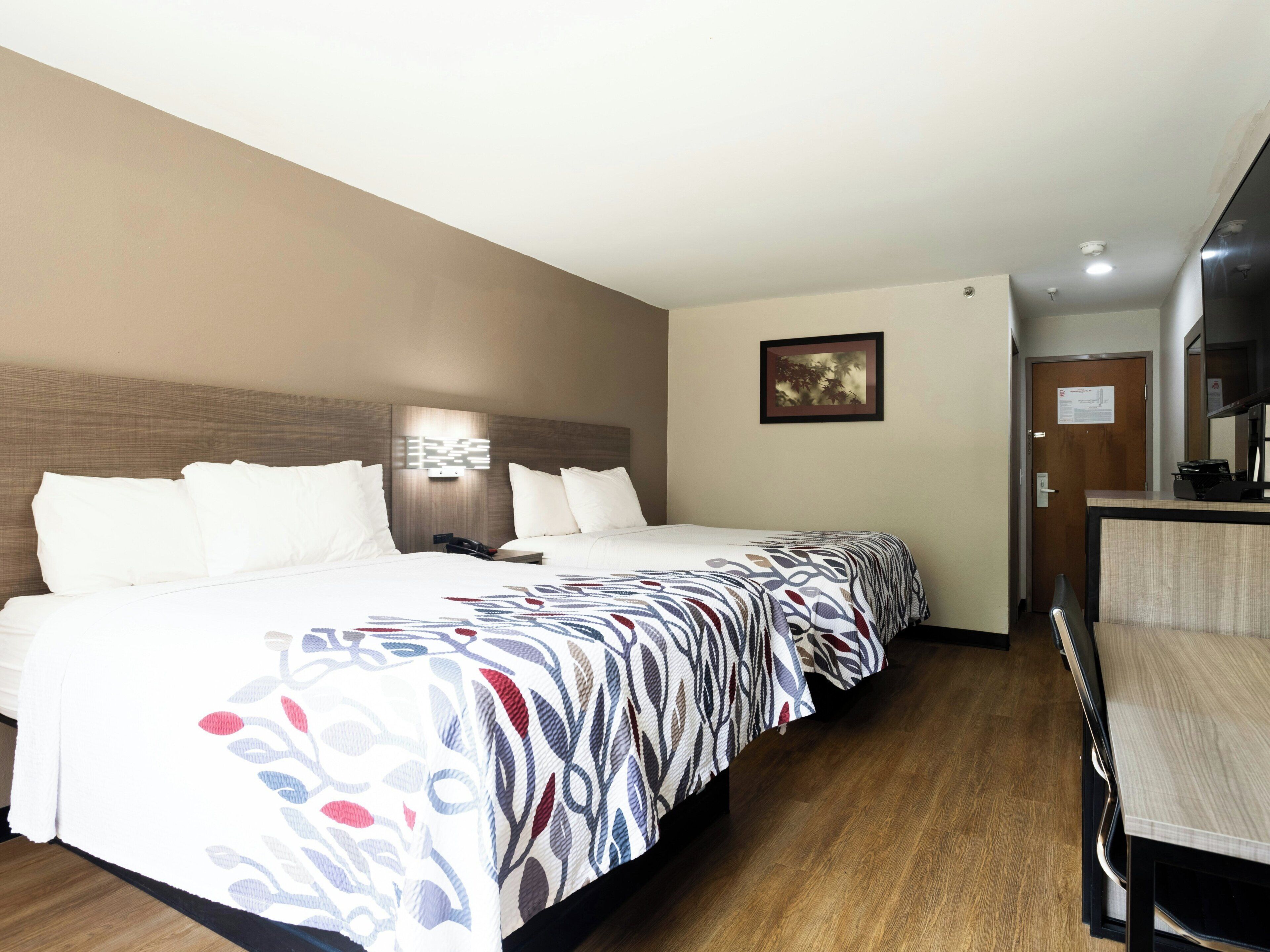 A hotel room with a large bed, a desk, and a mirror.