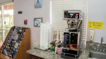 Una estación de café con una máquina de café, tazas y una exhibición de libros.