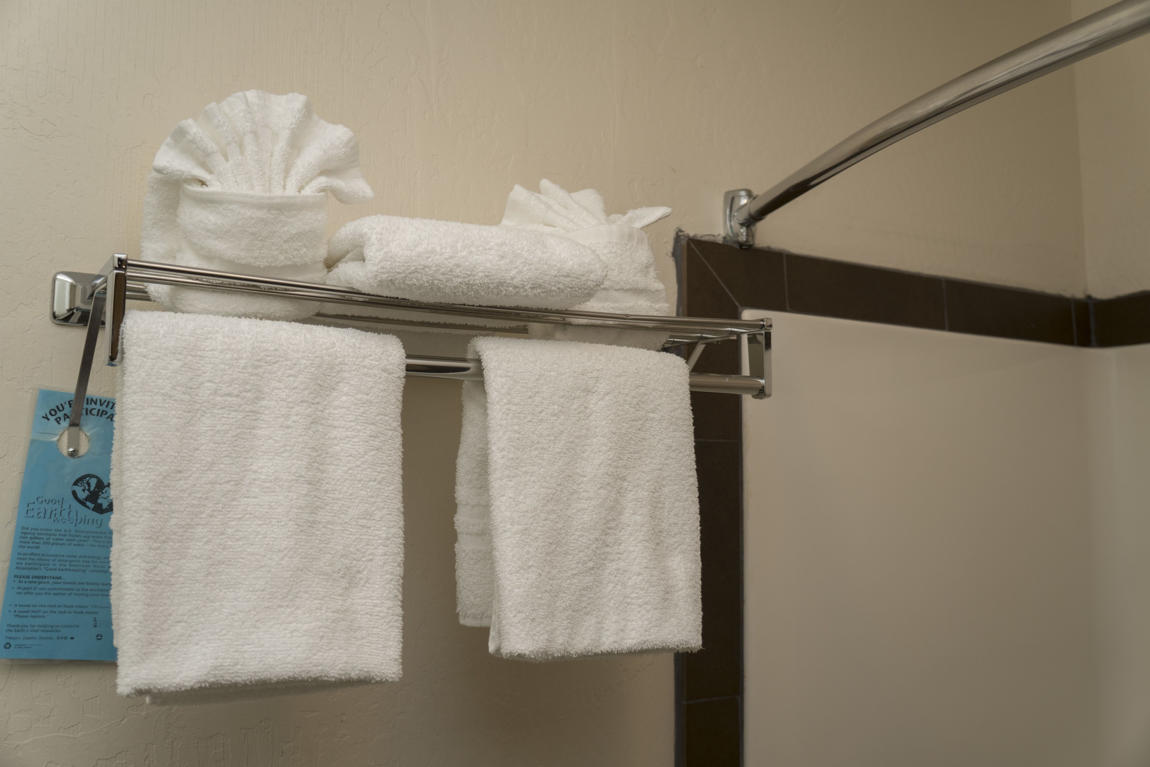 A bathroom with a towel rack holding two white towels and a bath mat.