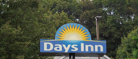 A Days Inn sign with a sunburst design, surrounded by trees.