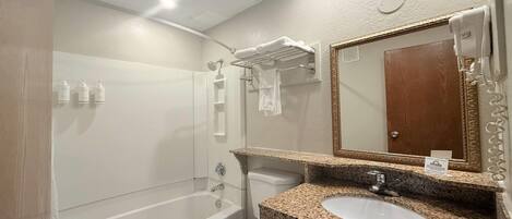 Une salle de bain avec une baignoire, des toilettes et un lavabo avec un plan de travail en granit.