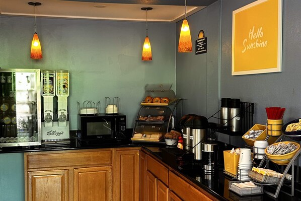 Un comptoir pour le petit-déjeuner équipé d’une machine à café, d’un four à micro-ondes et d’un présentoir de viennoiseries.
