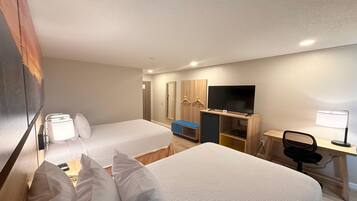 A hotel room with two beds, a desk with a chair, a TV, and a wardrobe.