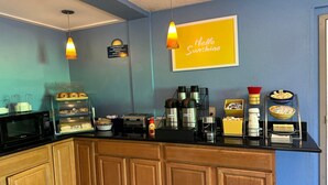A kitchen area with a counter, a microwave, a coffee machine, and a display case with pastries. - Days Inn by Wyndham Torrington (Torrington)