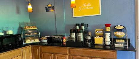 A breakfast bar with a coffee machine, toaster, and various food items.