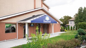 A Days Inn building with a blue awning, a lobby entrance, and a well-maintained lawn with various plants. - Days Inn by Wyndham Torrington (Torrington)