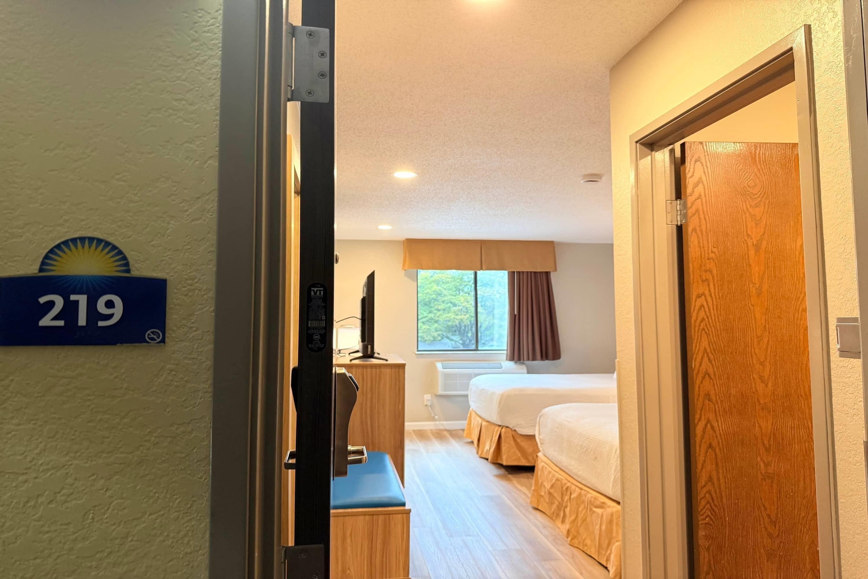 A hotel room with a bed, a desk, and a window with curtains.