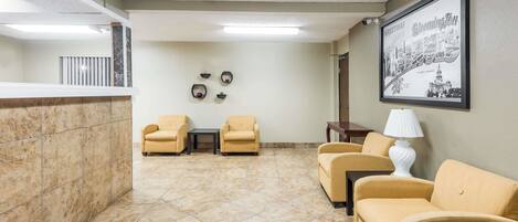 Un hall con sofás beige, un mostrador de recepción y un letrero de bienvenida enmarcado.