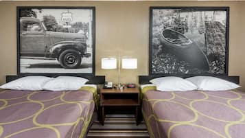 A hotel room with two beds, a nightstand with a lamp, and two framed pictures on the wall.