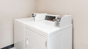 A front view of a white, wall-mounted washer and dryer unit with a control panel and a small window on the top. - Super 8 by Wyndham Bloomington/Normal (Bloomington)