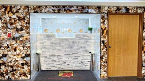 Zona de recepción con pared de mosaico de piedra, un mostrador de recepción y una puerta de madera.