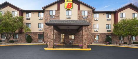 A Super 8 hotel with a brick facade, multiple windows, and a central entrance with a bench.
