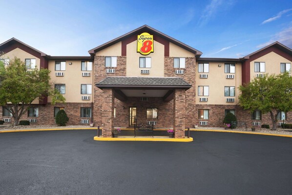 A Super 8 hotel with a brick facade, multiple windows, and a central entrance with a bench.