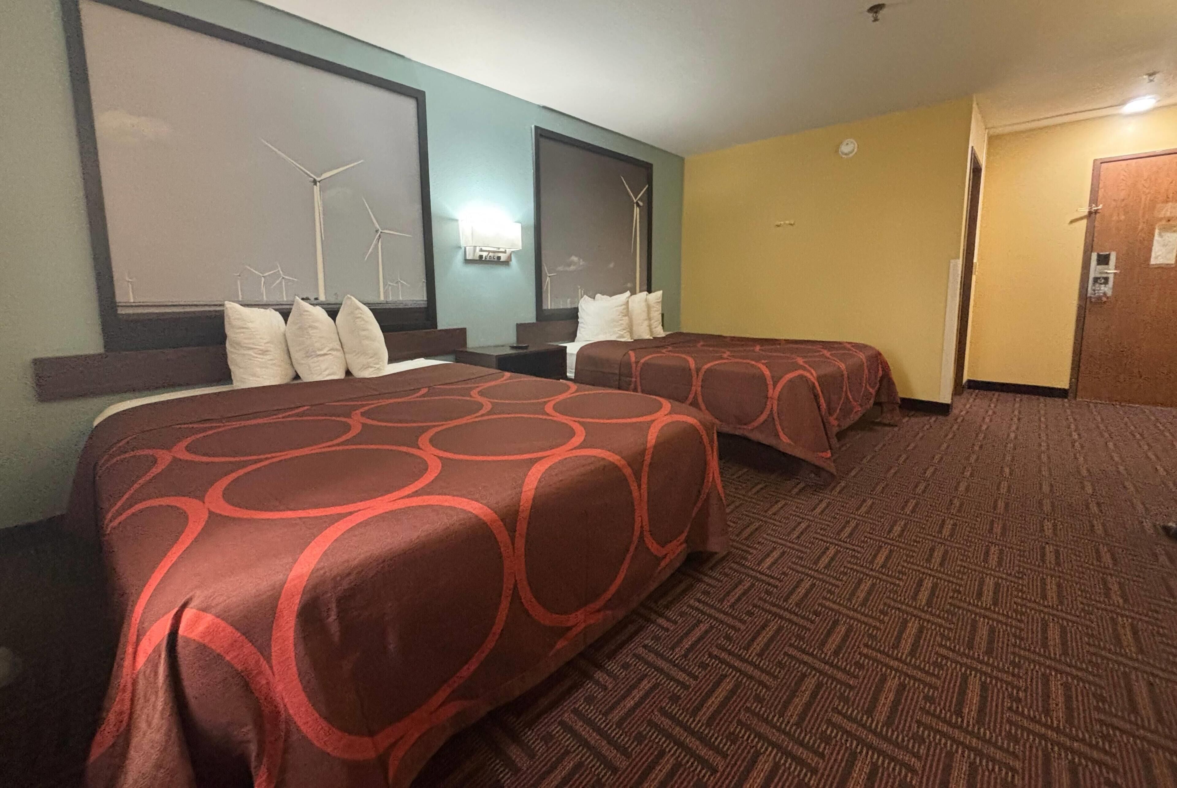 Ein Hotelzimmer mit zwei Betten, Teppichboden und einer Wand mit Windkraftanlagen.