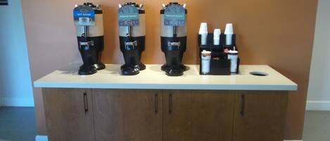 Een koffiehoek met drie koffieautomaten en een suikerdispenser.