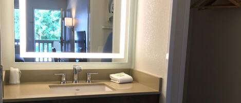 A bathroom with a large mirror, a sink, and a towel rack.