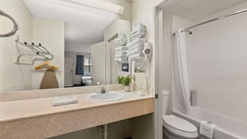 Ein modernes Badezimmer mit Waschbecken, Spiegel, Handtuchhalter und Dusche.