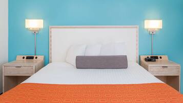 A hotel room with a bed, two bedside tables, and two wall-mounted lamps.