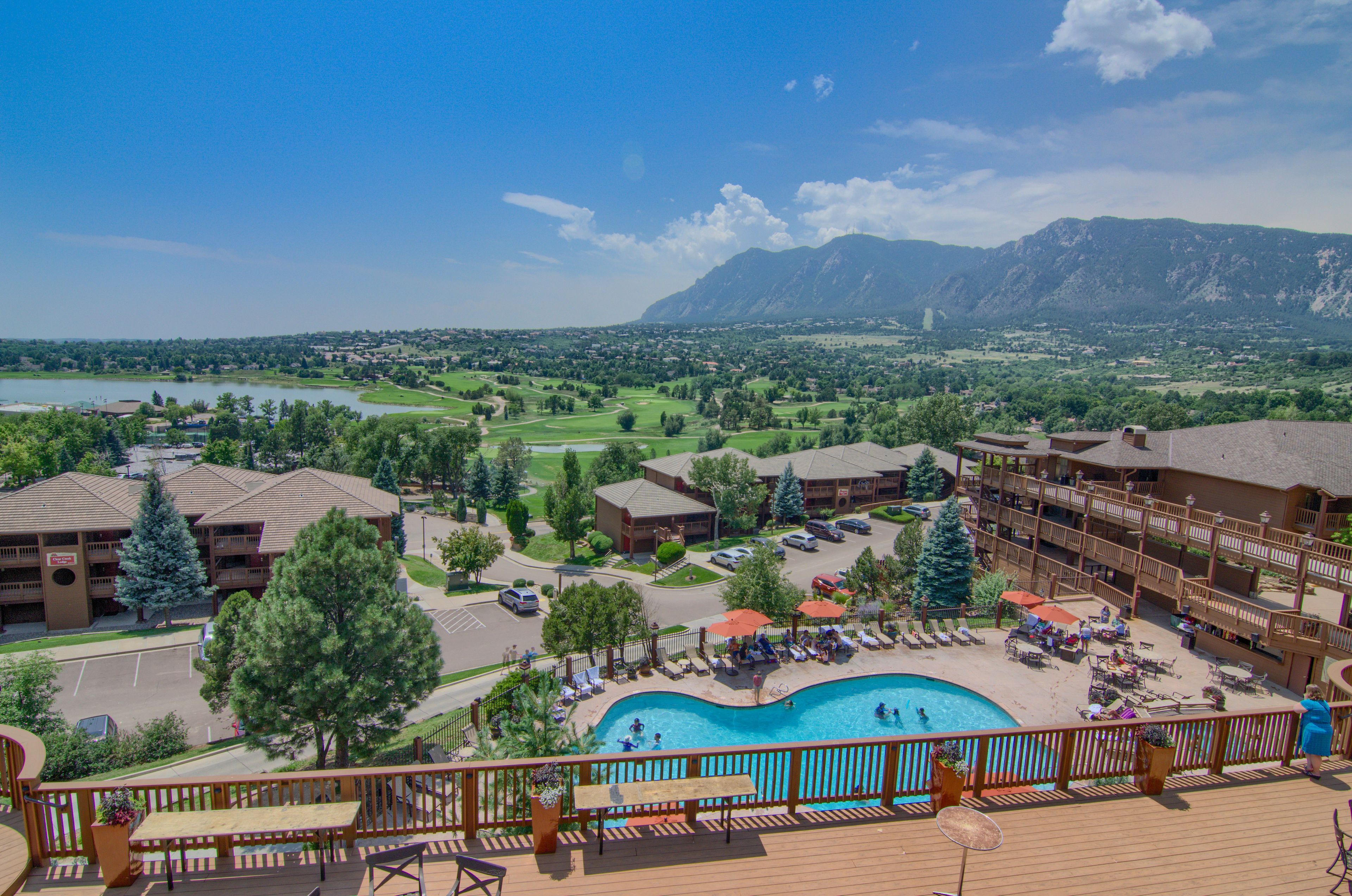 A resort with a pool, outdoor seating, and mountain views.