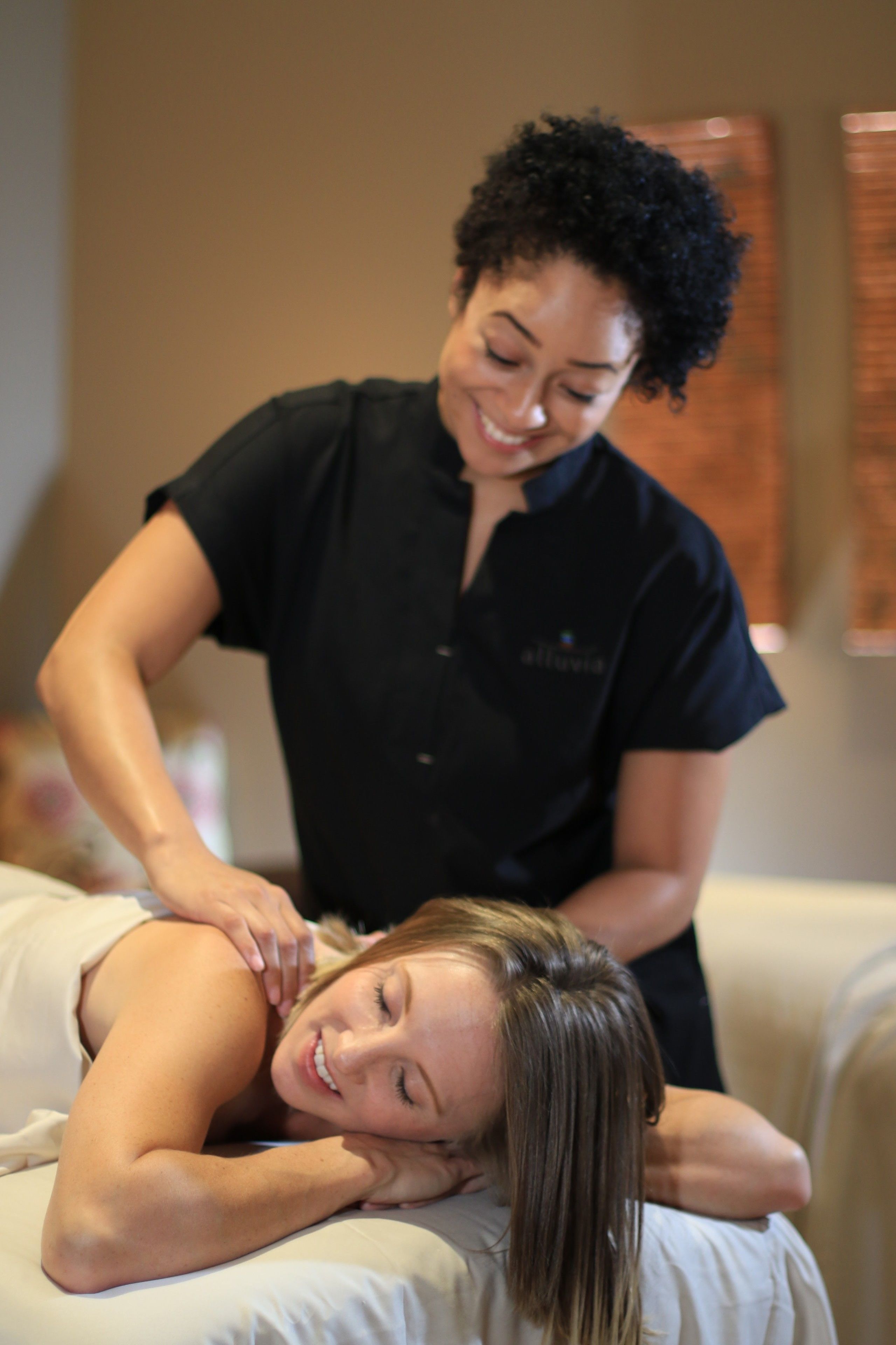 A massage therapy session in a room with a bed and a wall-mounted massage table.