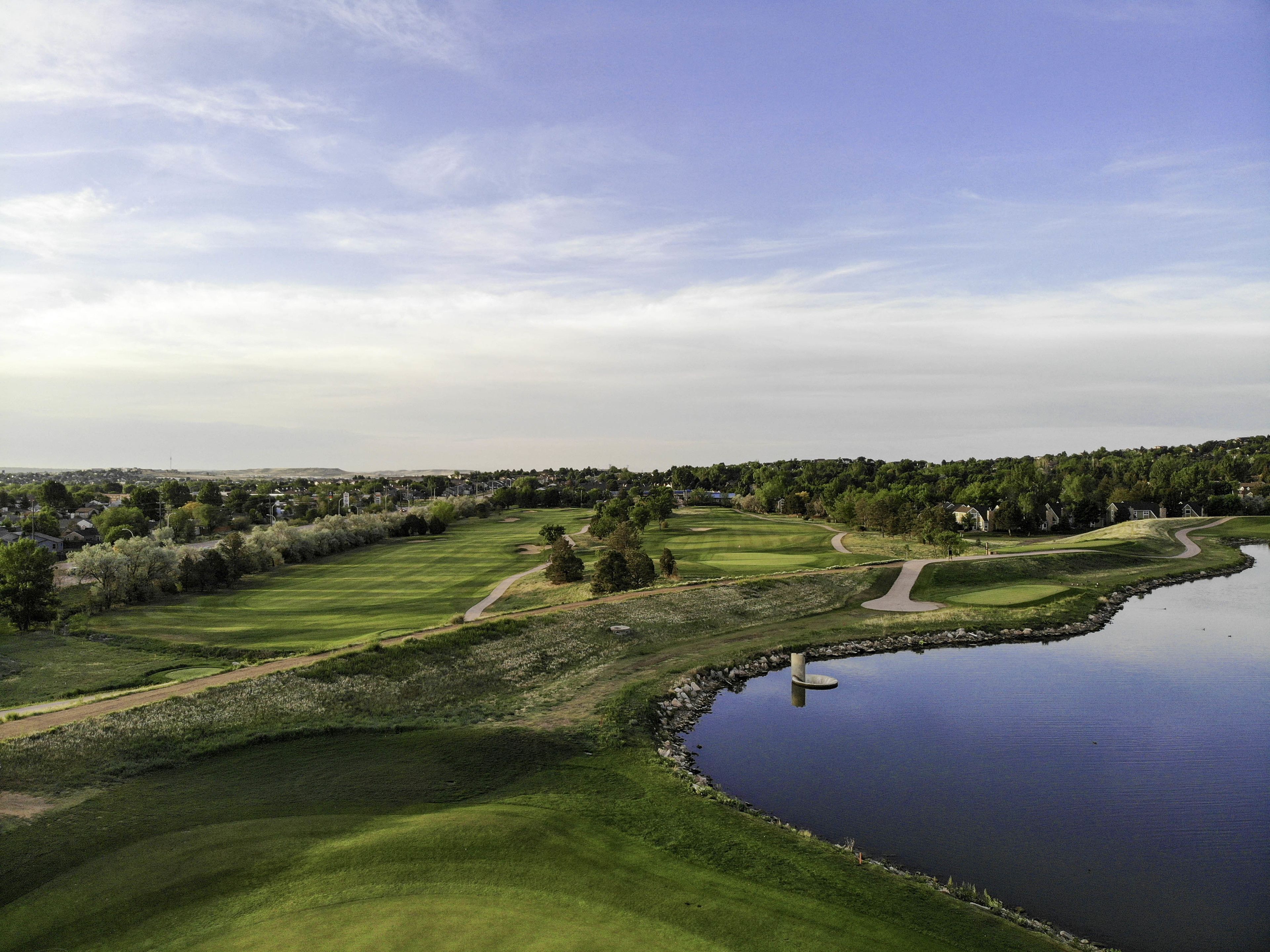 A golf course with a water body and a path leading to a bridge.