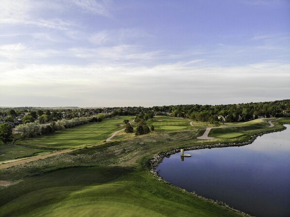 A golf course with a water body and a path leading to a bridge. - Cheyenne Mountain Resort, a Destination by Hyatt Hotels (Colorado Springs)