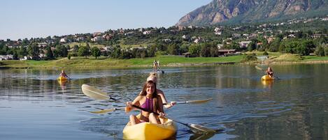 A group of people kayaking on a calm lake with a mountainous backdrop.