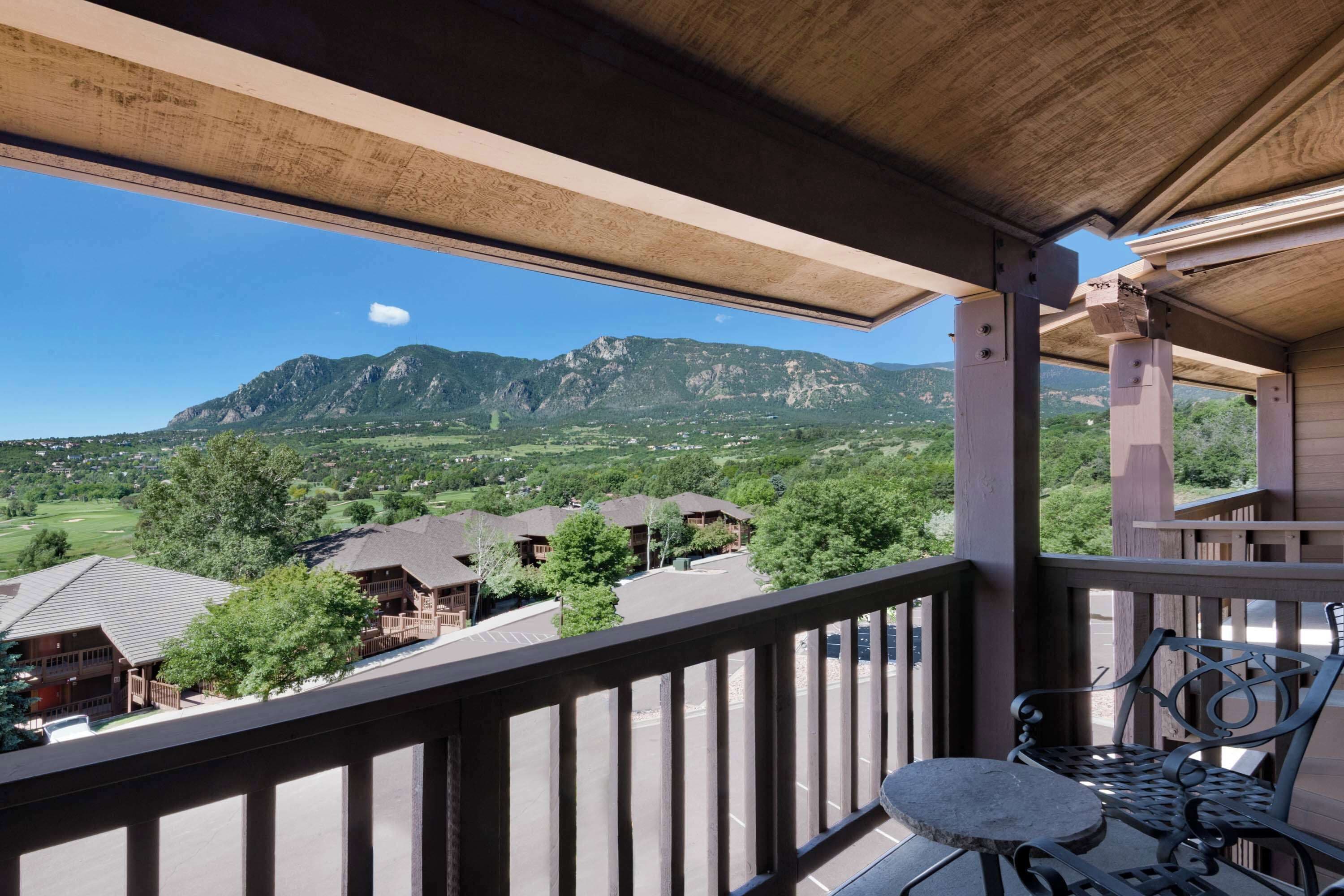 Un balcón de madera con vista a una montaña y edificios circundantes.
