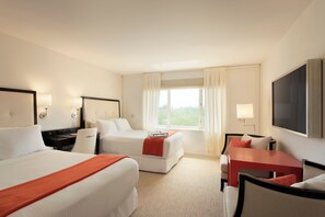 A hotel room with two beds, a desk, a TV, and a window with curtains. - The H Hotel (Midland)