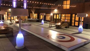 Un espace extérieur bien éclairé, aménagé avec des sièges et une patinoire de curling.