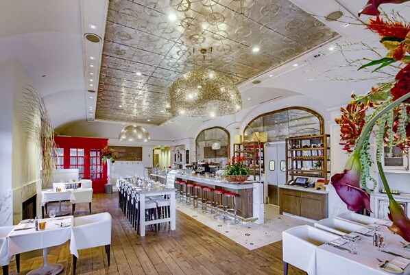 A restaurant with a high ceiling, white tables, and a bar area. - The H Hotel (Midland)