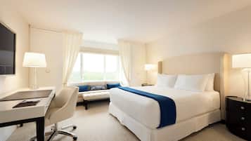 Une chambre d’hôtel avec un lit, un bureau, une chaise et un téléviseur fixé au mur.