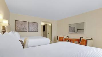 A hotel room with a large bed, a desk, a chair, and a mirror.