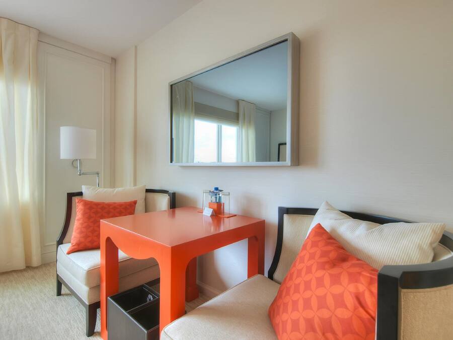 A hotel room with a sofa, a small table, a lamp, and a mirror.