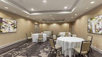 A conference room with round tables, chairs, and a carpeted floor.