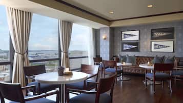 A modern dining area with round tables and chairs, a leather sofa, and framed Yale logos on the wall.