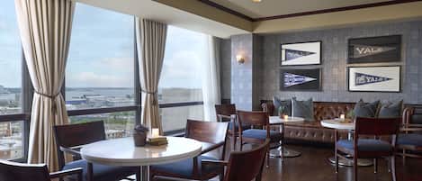 A modern dining area with round tables and chairs, a leather sofa, and framed Yale logos on the wall.