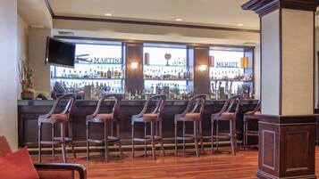 A bar area with wooden chairs and a counter displaying liquor bottles.