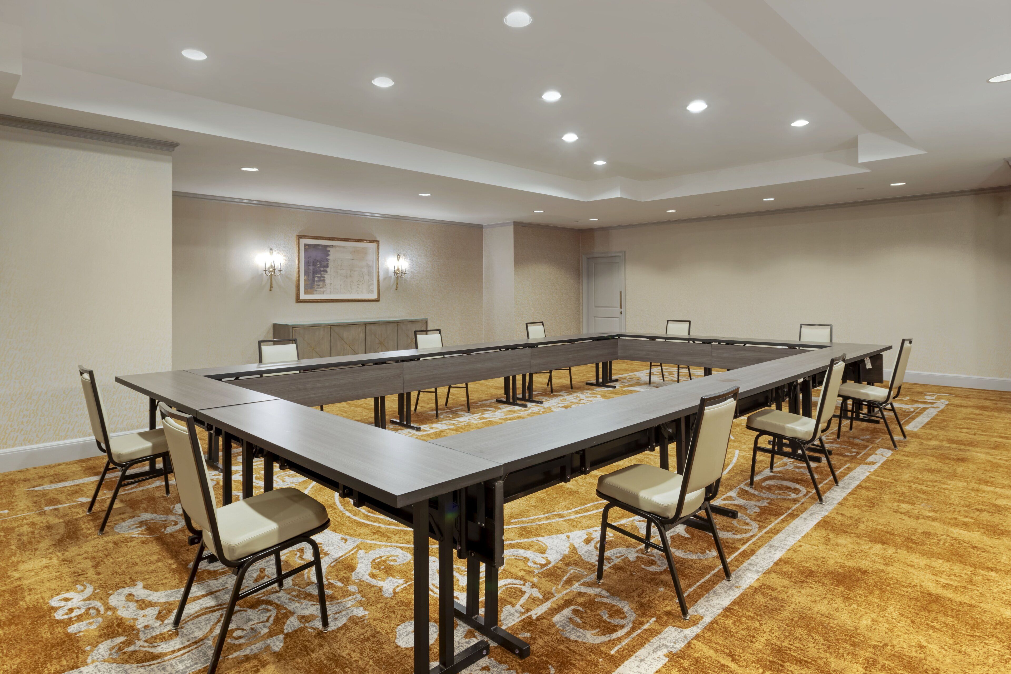 A conference room with a long table, chairs, and recessed lighting.