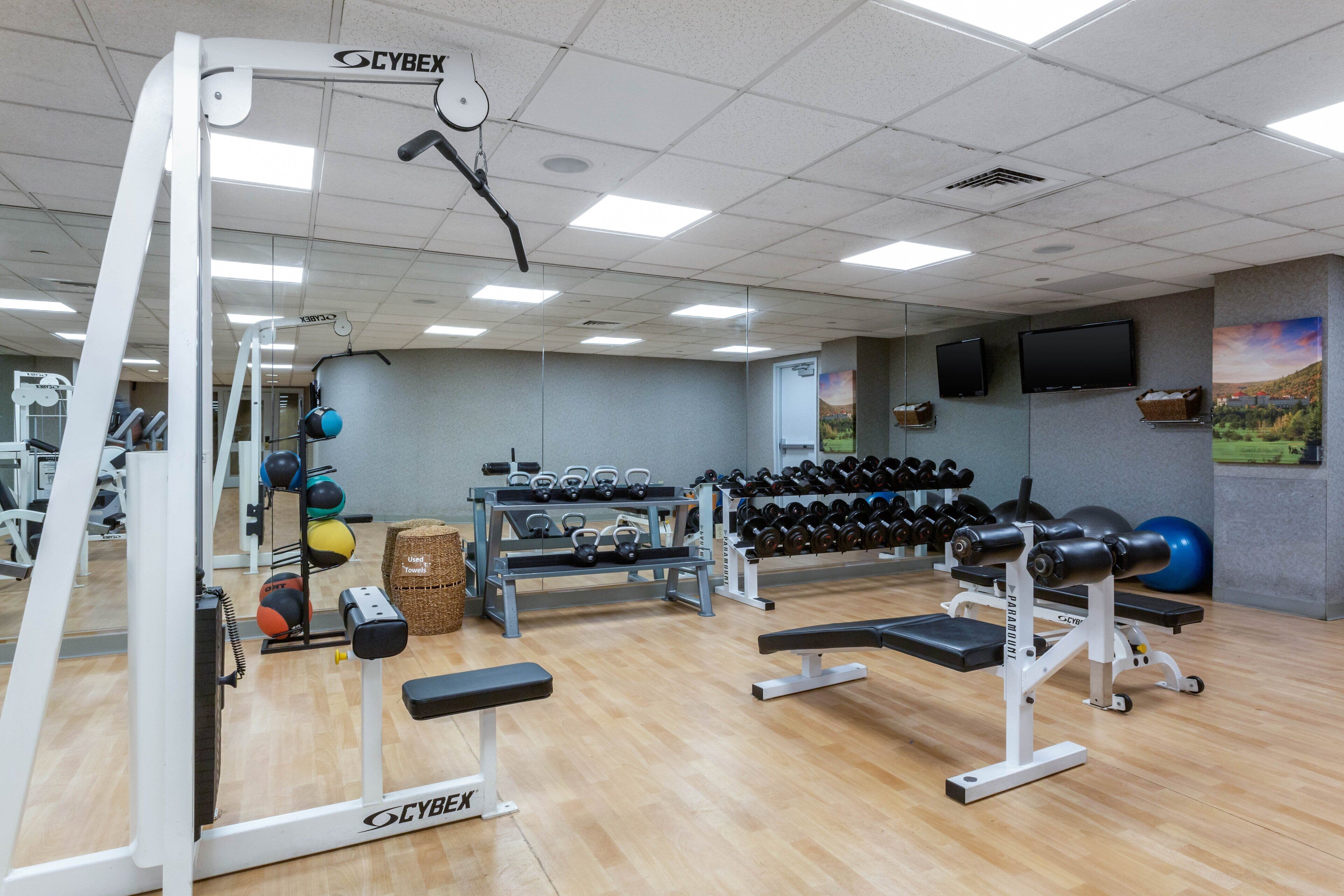 Une salle de sport équipée de divers appareils d’entraînement, notamment des haltères, des kettlebells et un banc.