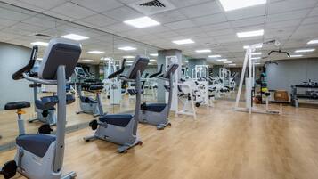 Uma academia com diversos equipamentos de exercício, incluindo esteiras e aparelhos de musculação, dispostos em fileiras.