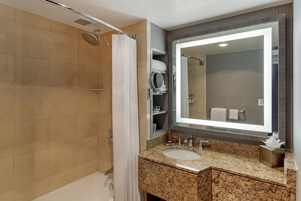 Un baño moderno con ducha a ras de suelo, un espejo grande y un lavabo con encimera de granito.