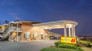 A Super 8 motel with a brick facade, a covered parking area, and a sign indicating the motel's name. - Super 8 by Wyndham Monroe West (West Monroe)