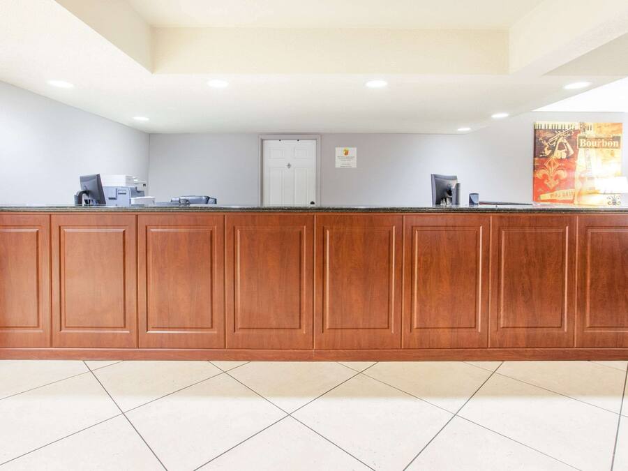 A reception area with a wooden reception desk, a white door, and a poster on the wall.