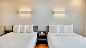 A hotel room with two beds, each with white linens and pillows, a nightstand with a phone, and wall-mounted lighting. - Motel 6 Los Angeles, CA - Los Angeles - LAX (Inglewood)
