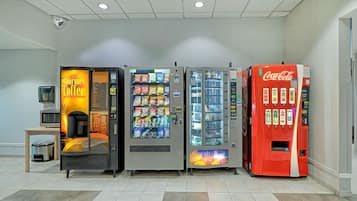 A row of vending machines including a coffee machine, snack dispensers, and a Coca-Cola machine.
