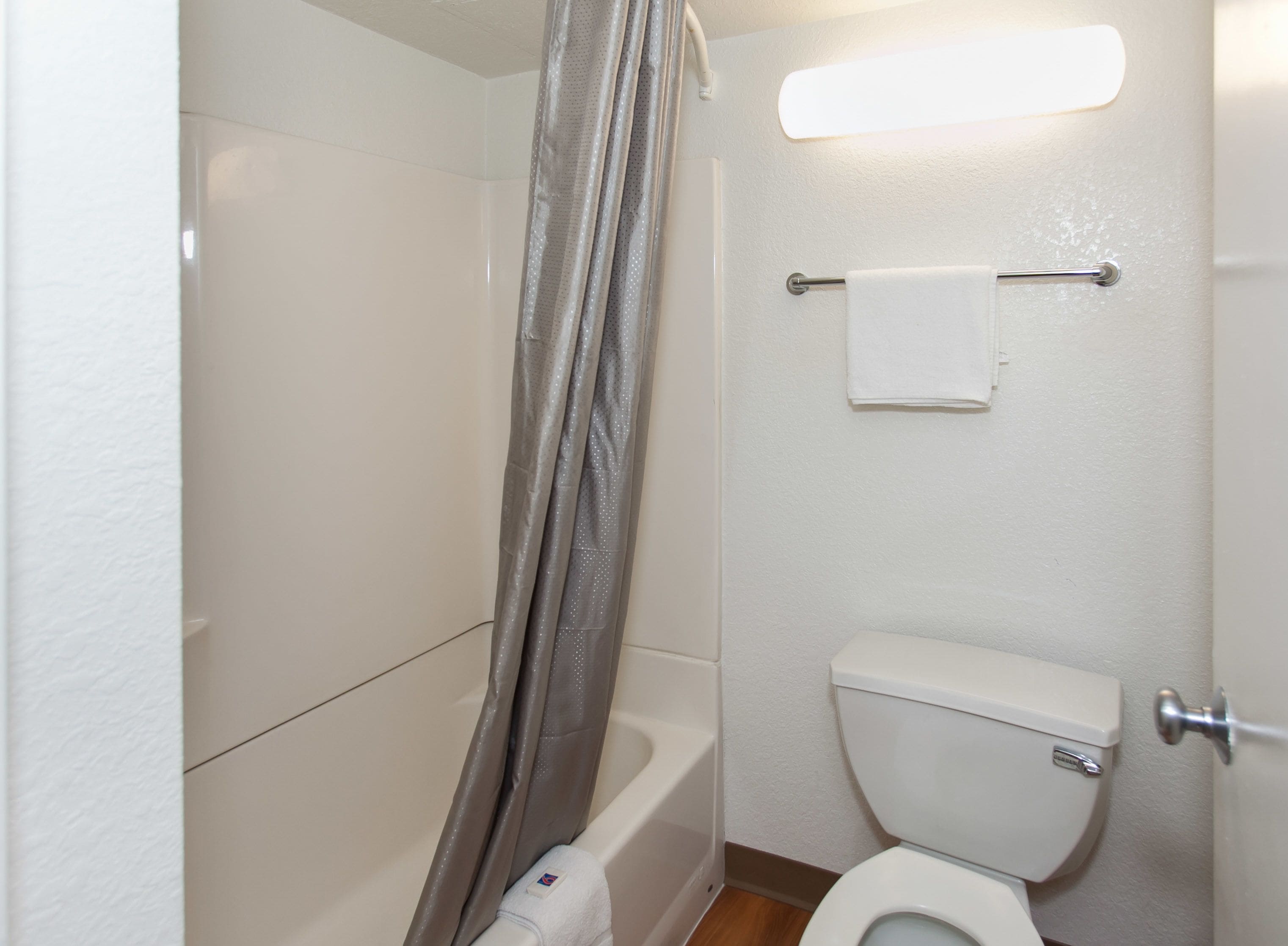 A small, clean bathroom with a shower, toilet, and towel rack.