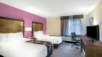 Habitación de hotel con dos camas, un escritorio con televisor, una silla y una ventana con cortinas.