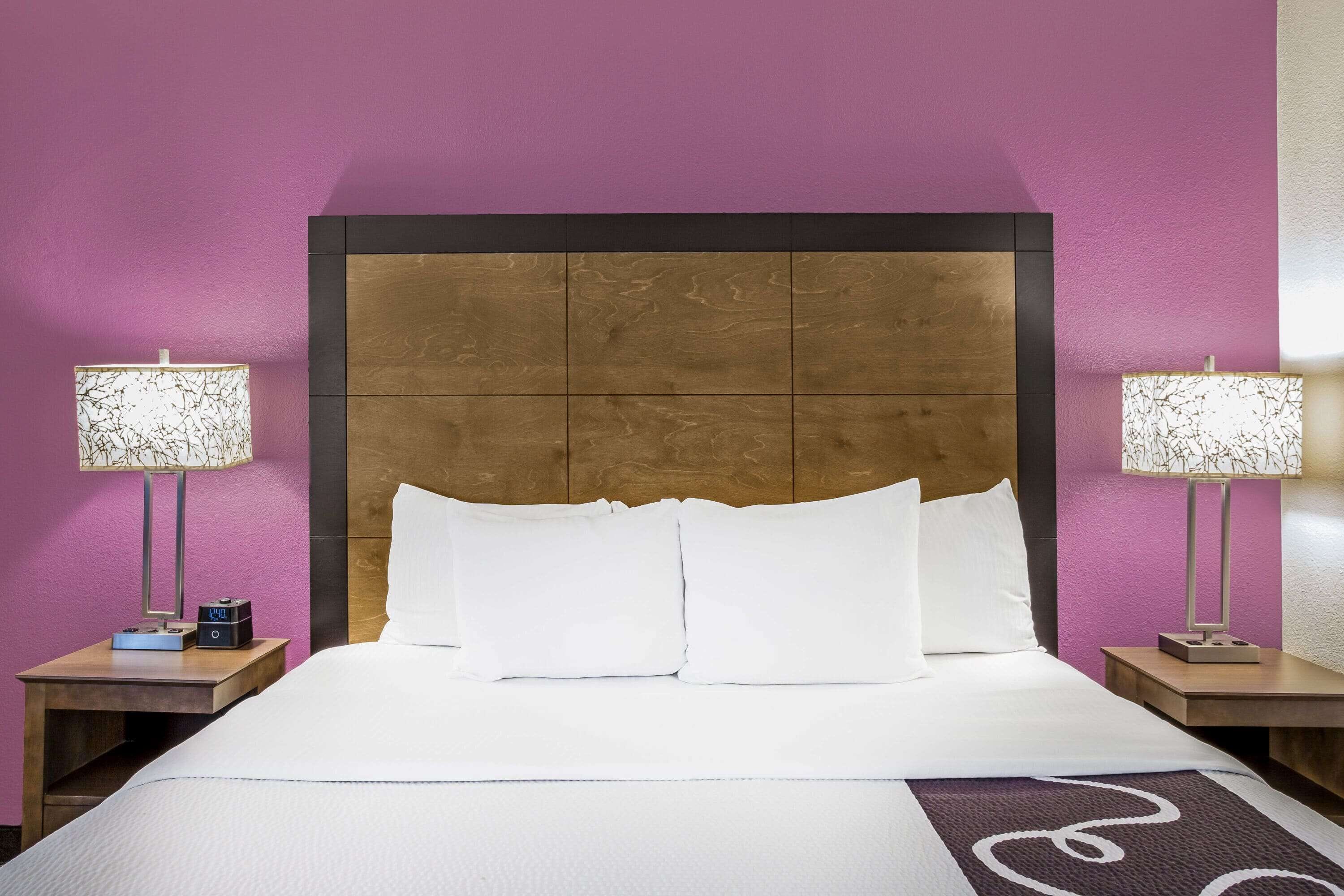 Una habitación de hotel con una cama grande, dos mesitas de noche y lámparas.