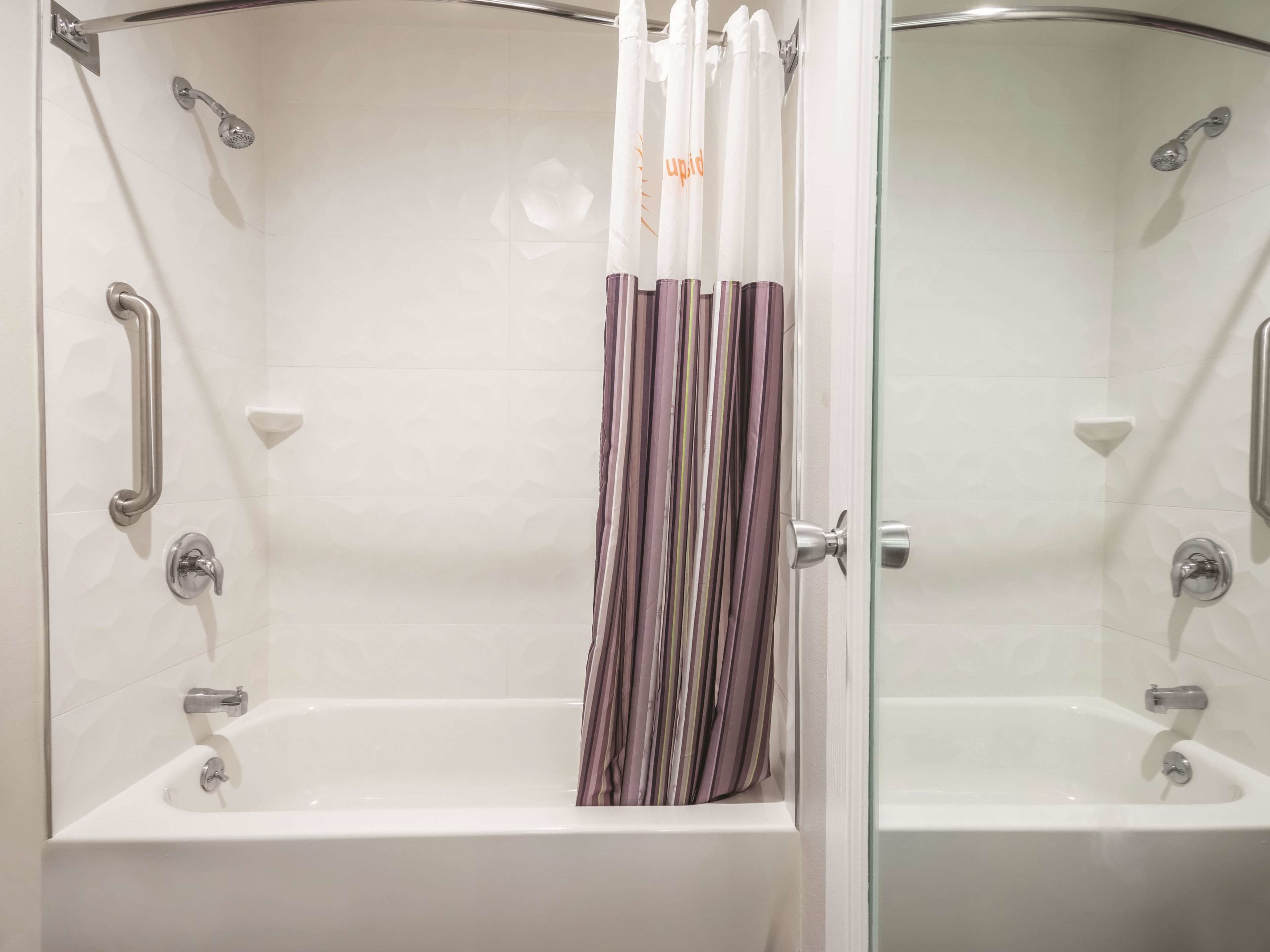 A modern bathroom with a glass shower enclosure, a white bathtub, and a striped shower curtain.